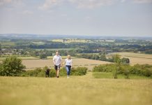 Loving Mature Couple Walking With Pet Dog Through Beautiful English Countryside In Oxfordshire England UK