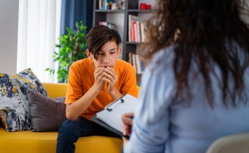 Female psychologist counseling teenage boy in office, Young people's mental health