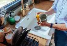 A senior man washing a mug with a kitchen sponge