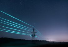 Electricity transmission towers with glowing wires against the starry sky.