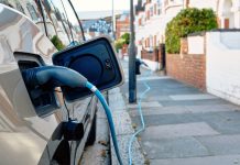 An electric car charges on a sunny day on a London street, embodying modern eco-friendly transportation in an urban setting.