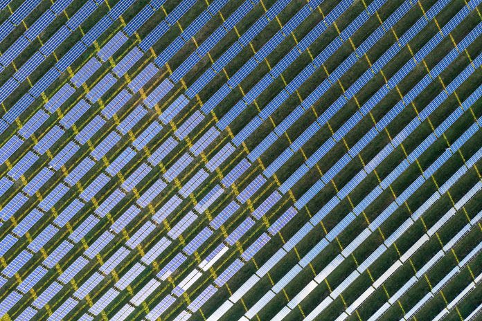 Top down view of rows of blue solar panels in a large solar power station.