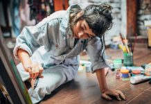 One woman, beautiful lady artist, painting on the floor in studio.