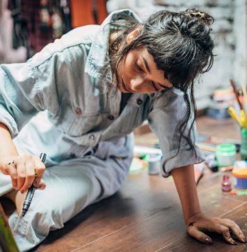 One woman, beautiful lady artist, painting on the floor in studio.