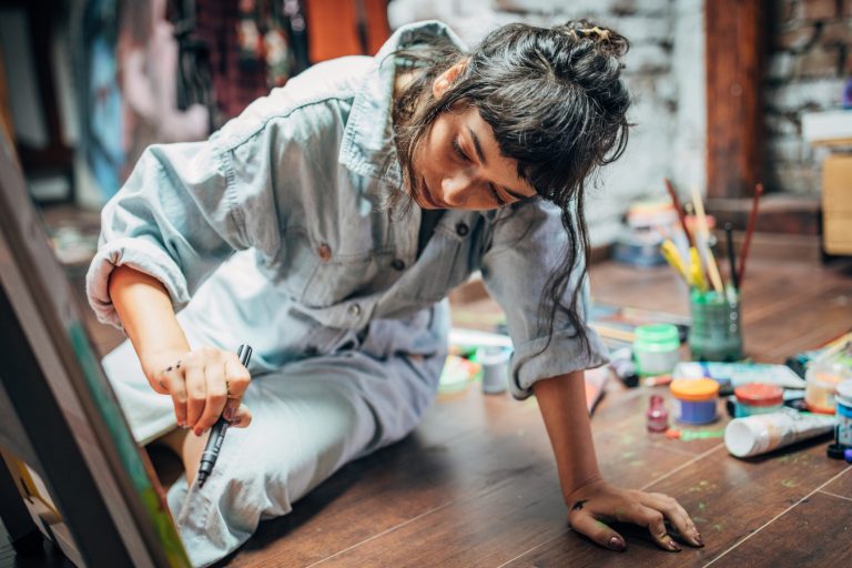 One woman, beautiful lady artist, painting on the floor in studio.