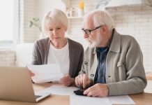 Serious caucasian old elderly senior couple grandparents family counting funds on calculator, doing paperwork, savings, paying domestic bills, mortgage loan, pension at home using laptop.