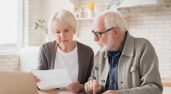 Serious caucasian old elderly senior couple grandparents family counting funds on calculator, doing paperwork, savings, paying domestic bills, mortgage loan, pension at home using laptop.