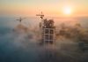 Aerial view of cement factory with high concrete plant structure and tower crane at industrial production site on foggy morning. Manufacture and global industry concept.