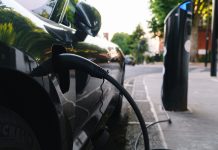 Black car recharging its lithium electric batteries at a free public station. pushing for electric vehicle accessibility