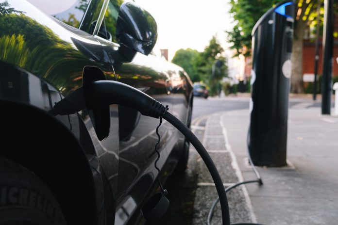 Black car recharging its lithium electric batteries at a free public station. pushing for electric vehicle accessibility