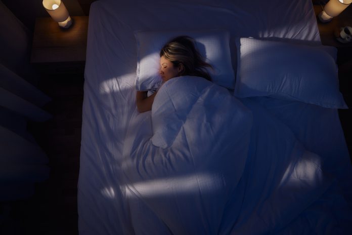 Above view of serene woman sleeping in bed at night.