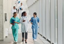 Happy female medical experts communicating while walking in a hallway of a hospital.