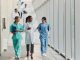 Happy female medical experts communicating while walking in a hallway of a hospital.