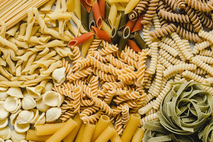 Table top view of variety of uncooked pasta. Full frame of different types of dried pasta on table.