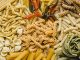 Table top view of variety of uncooked pasta. Full frame of different types of dried pasta on table.