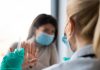 A female patient is refusing to take a shot from her doctor. She is holding her hands in front of her doctor as if defending herself from the syringe and the needle.