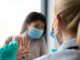 A female patient is refusing to take a shot from her doctor. She is holding her hands in front of her doctor as if defending herself from the syringe and the needle.