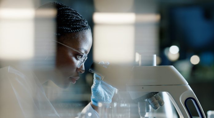 Scientist, microscope and analysis in lab for healthcare, innovation and development in stem cell research. Black woman, investigation and experiment with biotech for dna, exam or test for bacteria