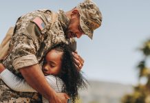 Affectionate military reunion between father and daughter. Emotional military dad embracing his daughter on his homecoming. Army soldier receiving a warm welcome from his child after deployment.