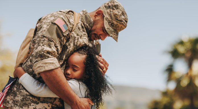 Affectionate military reunion between father and daughter. Emotional military dad embracing his daughter on his homecoming. Army soldier receiving a warm welcome from his child after deployment.