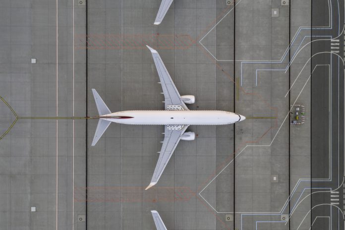 Top down view on comercial airplane in the parking lot of the airport apron, waiting for services maintenance, refilling fuel services after airspace lock down