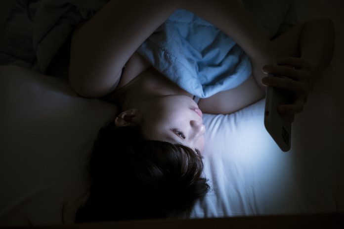 Woman Using Cellphone In Bed At Night