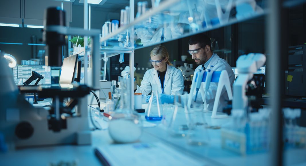 Team of Medical Research Scientists Conduct Experiments with Help of Microscope, Test Tubes, Micropipette and Desktop Computer. Modern Biological Applied Science Laboratory with Diverse Colleagues.