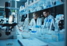 Team of Medical Research Scientists Conduct Experiments with Help of Microscope, Test Tubes, Micropipette and Desktop Computer. Modern Biological Applied Science Laboratory with Diverse Colleagues.