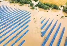 Aerial view of flooded solar power station with dirty river water in rain season.