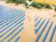 Aerial view of flooded solar power station with dirty river water in rain season.