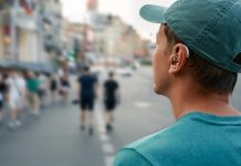 Human life with a hearing aid. Young man with a hearing aid behind the ear in a noisy city hears people around well