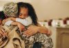 Soldier embracing his wife and kids on his homecoming. Serviceman receiving a warm welcome from his family after returning from deployment. Military family having an emotional reunion.