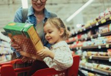 Portrait of a Young Girl Holding a Box of Cereal While Shopping With Mom at the Supermarket