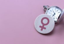 Menopause concept. Women symbol over a watch. Healthcare and medical for women. Pink background with copy space.