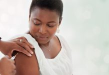 Black woman, covid vaccine injection and mockup space in hospital with doctor, nurse and blurred background. African patient, medic and medical mock up for healthcare, wellness and public service