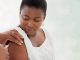 Black woman, covid vaccine injection and mockup space in hospital with doctor, nurse and blurred background. African patient, medic and medical mock up for healthcare, wellness and public service