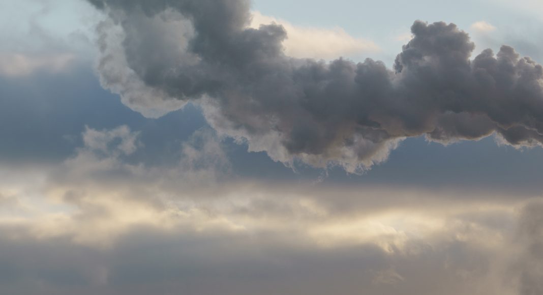 Heat station pipes, smoke. Smoking pipes, white smoke. Gray dramatic sky sky as background. Chimneys, concept of industry and ecology, heating season, global warming. Panoramic image