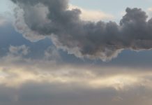 Heat station pipes, smoke. Smoking pipes, white smoke. Gray dramatic sky sky as background. Chimneys, concept of industry and ecology, heating season, global warming. Panoramic image