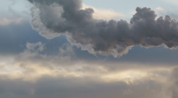 Heat station pipes, smoke. Smoking pipes, white smoke. Gray dramatic sky sky as background. Chimneys, concept of industry and ecology, heating season, global warming. Panoramic image