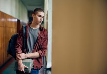 Sad teenage boy thinking of something while standing in hallway at high school. Copy space. article covering: Right-wing ethno-nationalists and jihadi Salafists