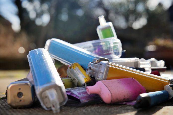 Collection of discarded vapes on a concrete background