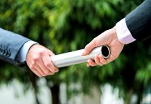 Businesswoman passing baton to a businesswoman outdoors.