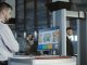 Man in uniform standing at counter at checking point and watching at monitor with x-ray of luggage.