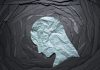 Negative emotion image. Person head shaped paper on black torn paper background.