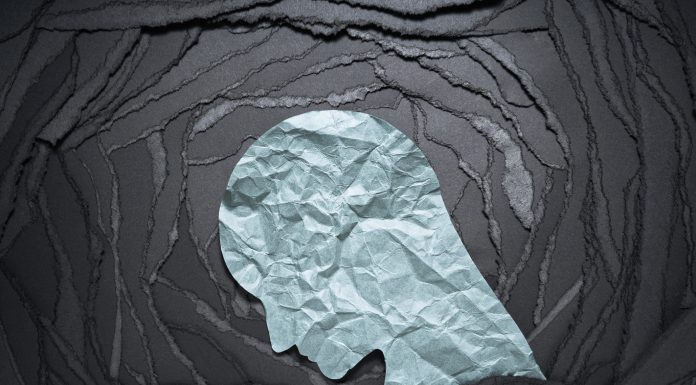 Negative emotion image. Person head shaped paper on black torn paper background.