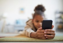 African American Girl Using Smartphone on Floor