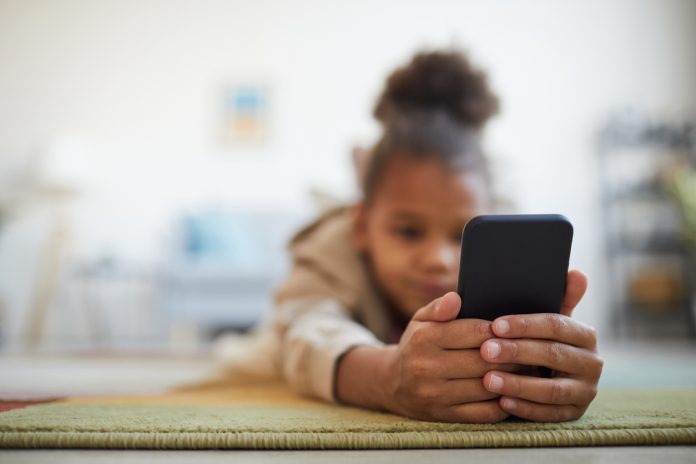 African American Girl Using Smartphone on Floor