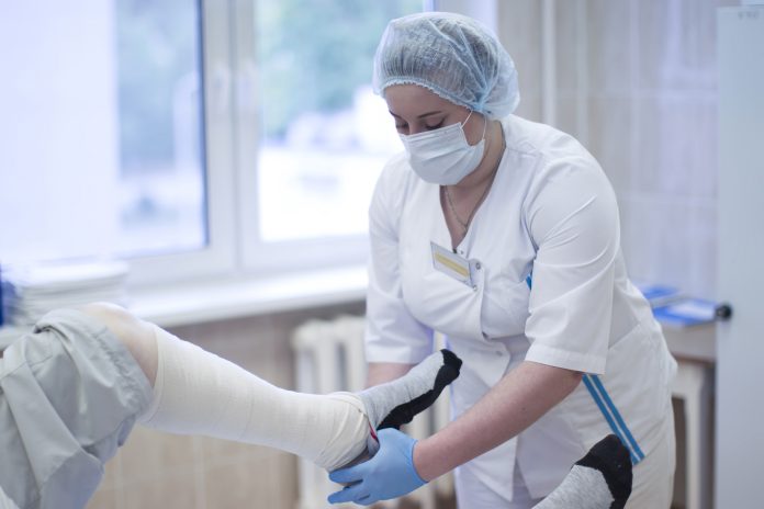 The nurse is bandaging the patient's leg. Leg fracture. Man in a surgical hospital for bandaging.