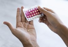 Close-up of young woman's hand holding birth control pills