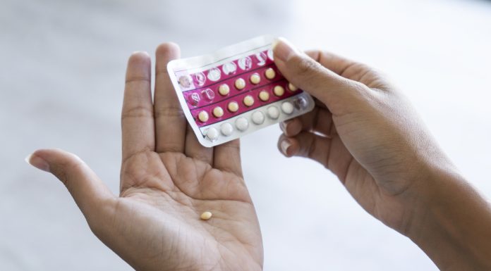 Close-up of young woman's hand holding birth control pills